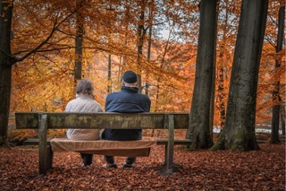 Renterpaar sitzt im Herbst auf Parkbank und denkt über die eigene Rentenlücke nach